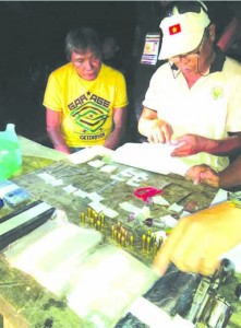 DRUG LORD. Eddie T. VaÃ±o, (I) watches the inventory of shabu and firearms seized during his arrest in Carmen town yesterday afternoon.